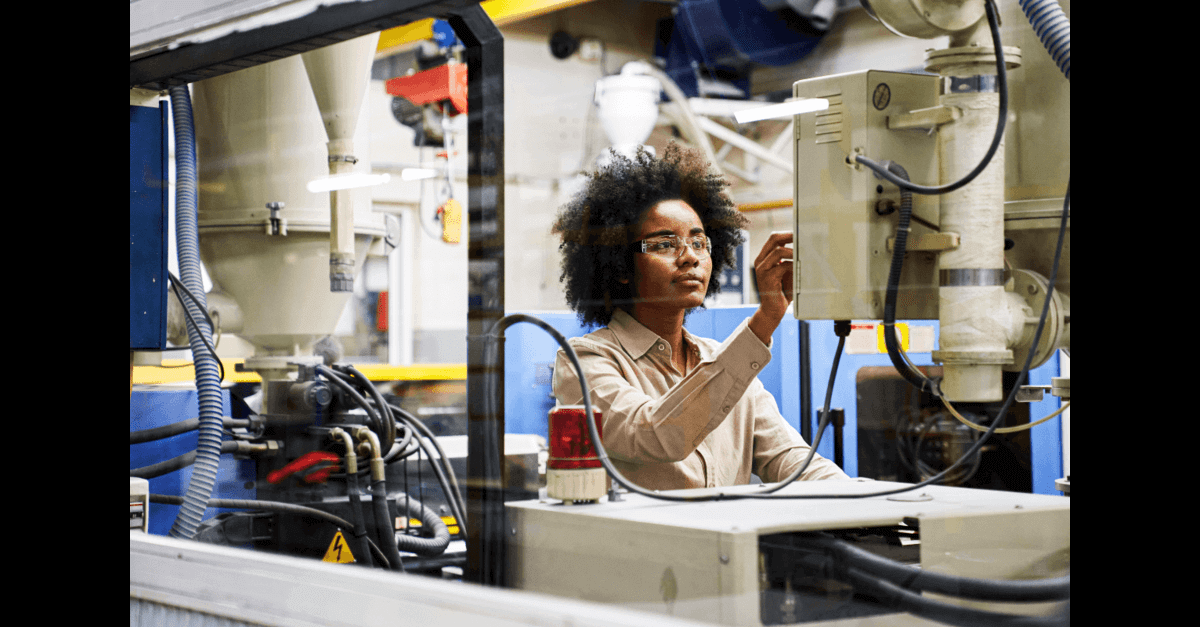 Young black woman monitors a factory machine for preventive maintenance